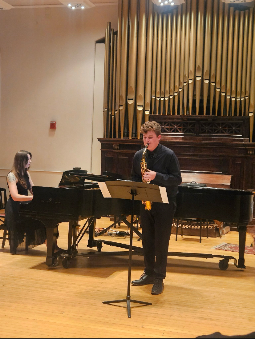 Nathaniel performing saxophone at a recital hall